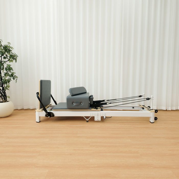 The reformer in slate grey upholstery, colour 319, side view in a studio.