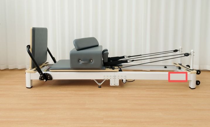 A white reformer frame with the logo position marked on its side, at the head end.